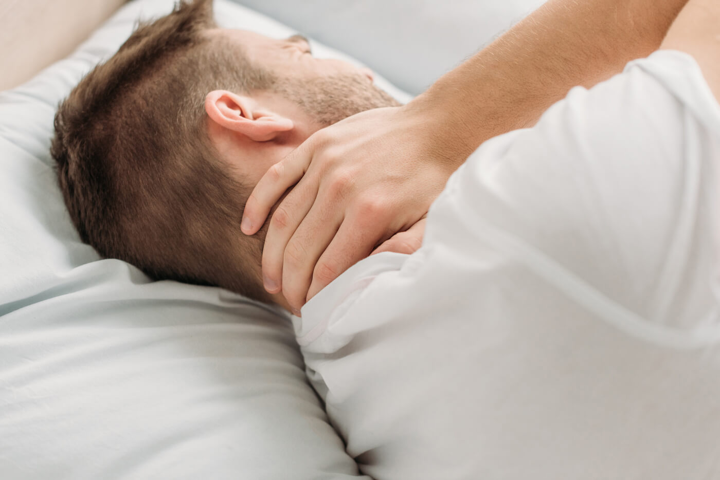 Jonge man die is wakker geworden met nekpijn na het slapen