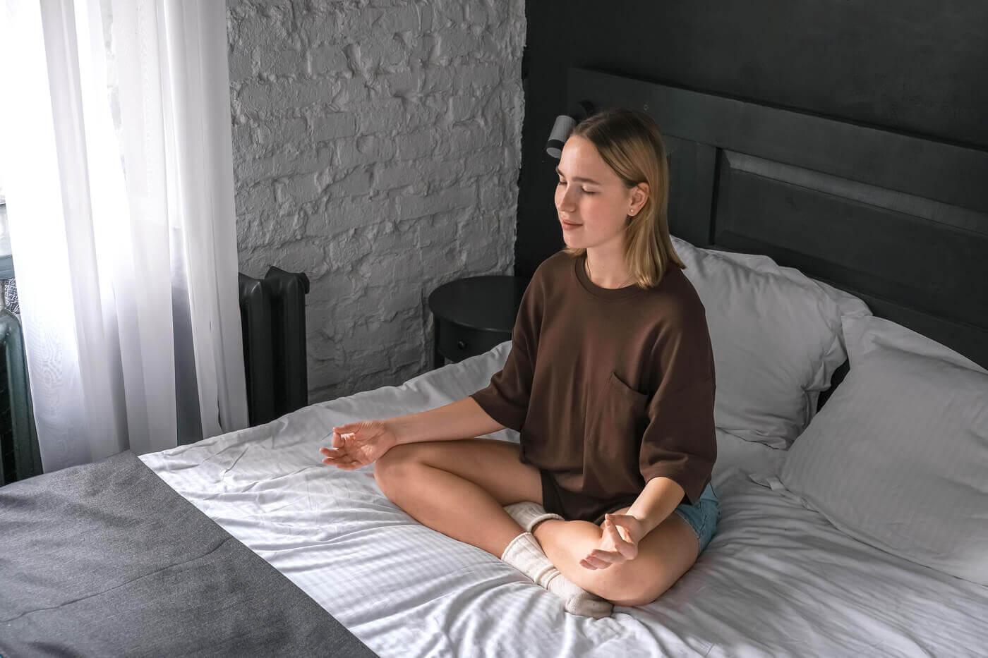 Vrouw die voor het slapen mediteert op bed